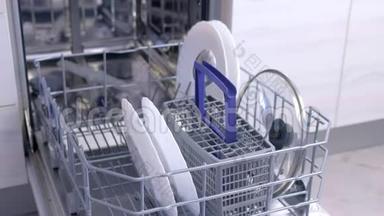 人把白色餐具和餐具放在洗碗机的篮子里，高速。